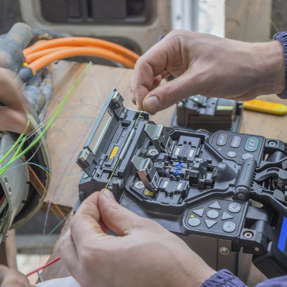 Fibre optic technician splicing fibers. Splicing two fibers using the fusion splicer.